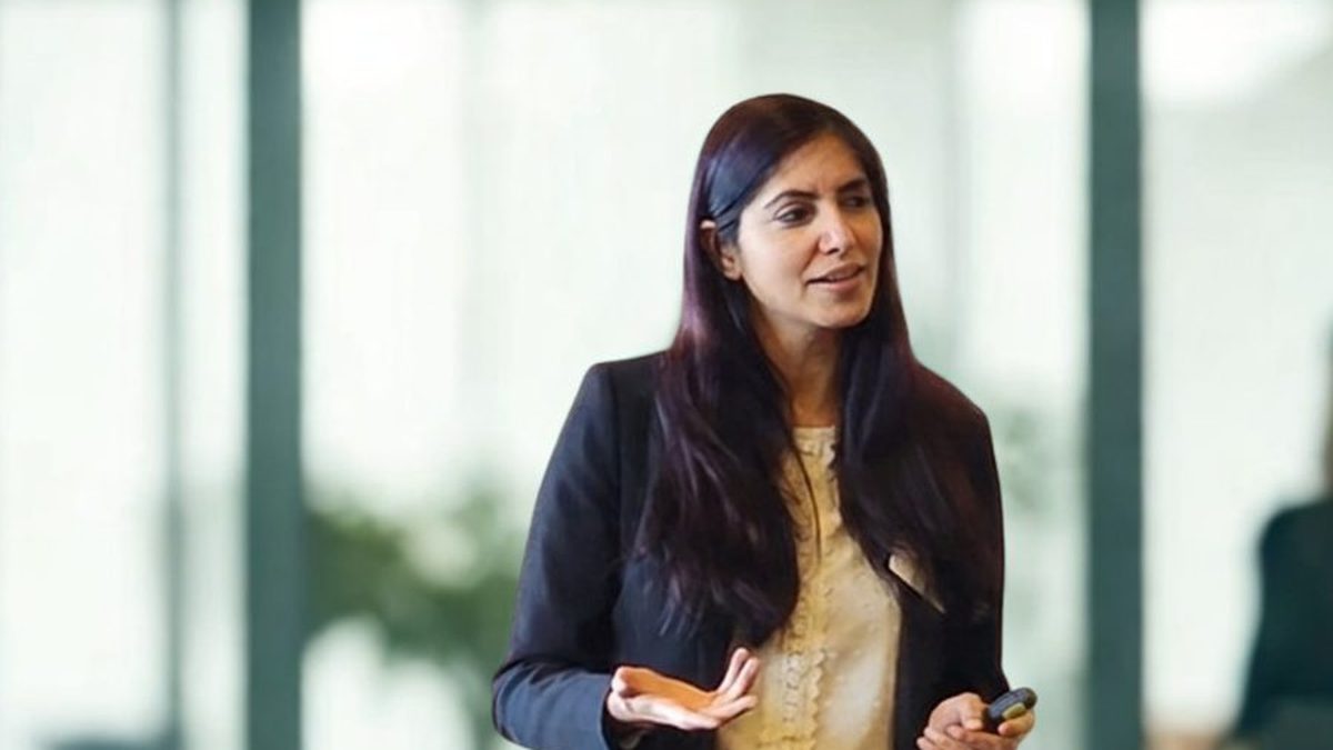 Kanika Vasudeva, LinkedIn Strategist and Mentor, presenting to a team in a bright office with a clicker in her hand, the kind of session where she teaches sales teams a shared system for bringing in business through LinkedIn.