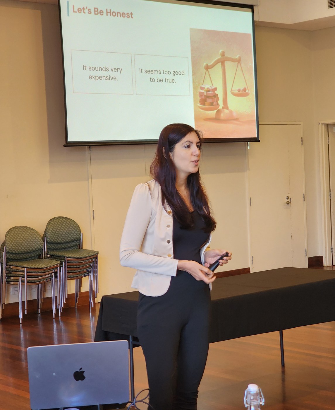 Kanika Vasudeva presenting to a room, with a slide headed Let's Be Honest behind her showing two common objections.